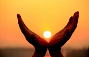 hands cusping sun at sunset